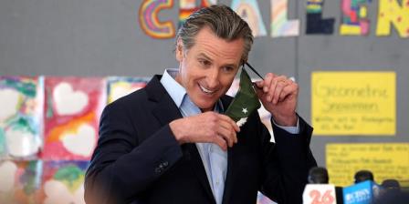 California Gov. Gavin Newsom removing his mask before speaking during a news co<em></em>nference after he toured the newly reopened Ruby Bridges Elementary School on March 16 in Alameda.
