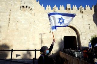 An Israeli woman holds a flag by Damascus gate just outside Jerusalem's Old City June 15, 2021. REUTERS/Ro<em></em>nen Zvulun/File Photo