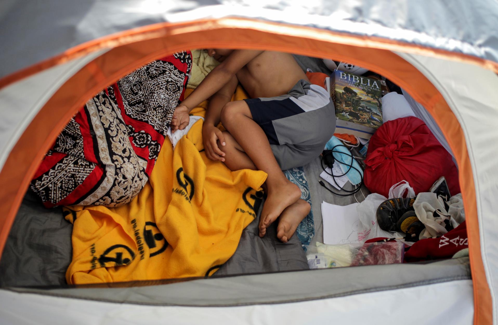 An asylum-seeking migrant youth, who was apprehended and returned to Mexico under Title 42 after crossing the border from Mexico into the U.S., rests in a public square wher<em></em>e hundreds of migrants live in tents, in Reynosa, Mexico June 9, 2021. Picture taken June 9, 2021. REUTERS/Daniel Becerril