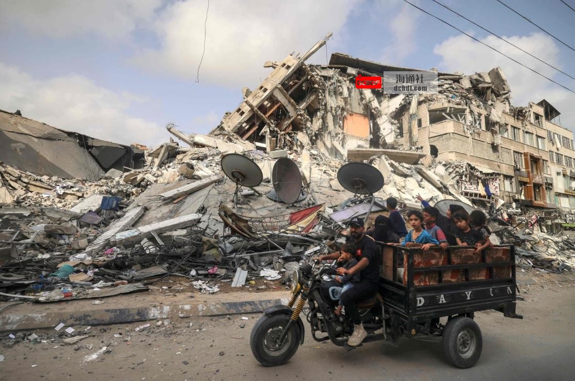 A Palestinian man transports children in a tricycle past the Al-Shuruq building, destroyed by an Israeli airstrike, in Gaza City, the Gaza Strip, Palestine, May 21, 2021. (AFP Photo)
