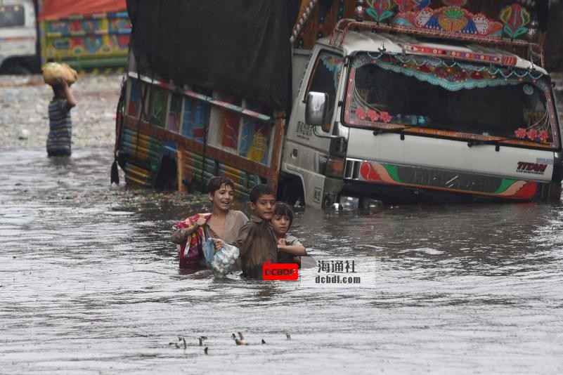 Children wade along a flooded street after a heavy downpour in Lahore, Pakistan, on Sept. 11. | AFP-JIJI