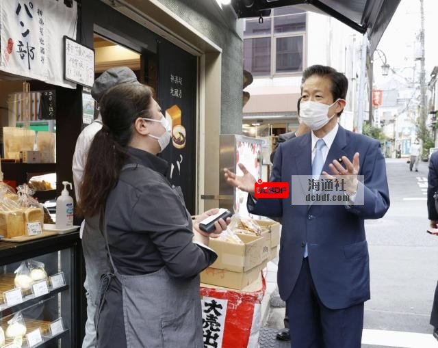 Natsuo Yamaguchi, leader of Komeito party, talks to a shop owner in Kagurazaka district of Tokyo on Saturday. | KYODO