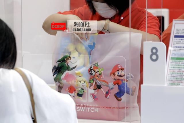 A store attendant puts a box of Nintendo Co. Switch game co<em></em>nsole in a shopping bag at the company's Nintendo TOKYO store. | BLOOMBERG