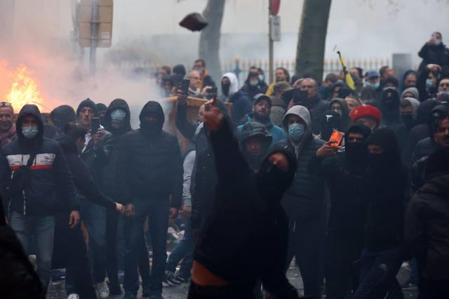 A protester throws sto<em></em>nes toward riot police as clashes erupt during a demo<em></em>nstration against COVID-19 measures in Brussels on Sunday.  | AFP-JIJI