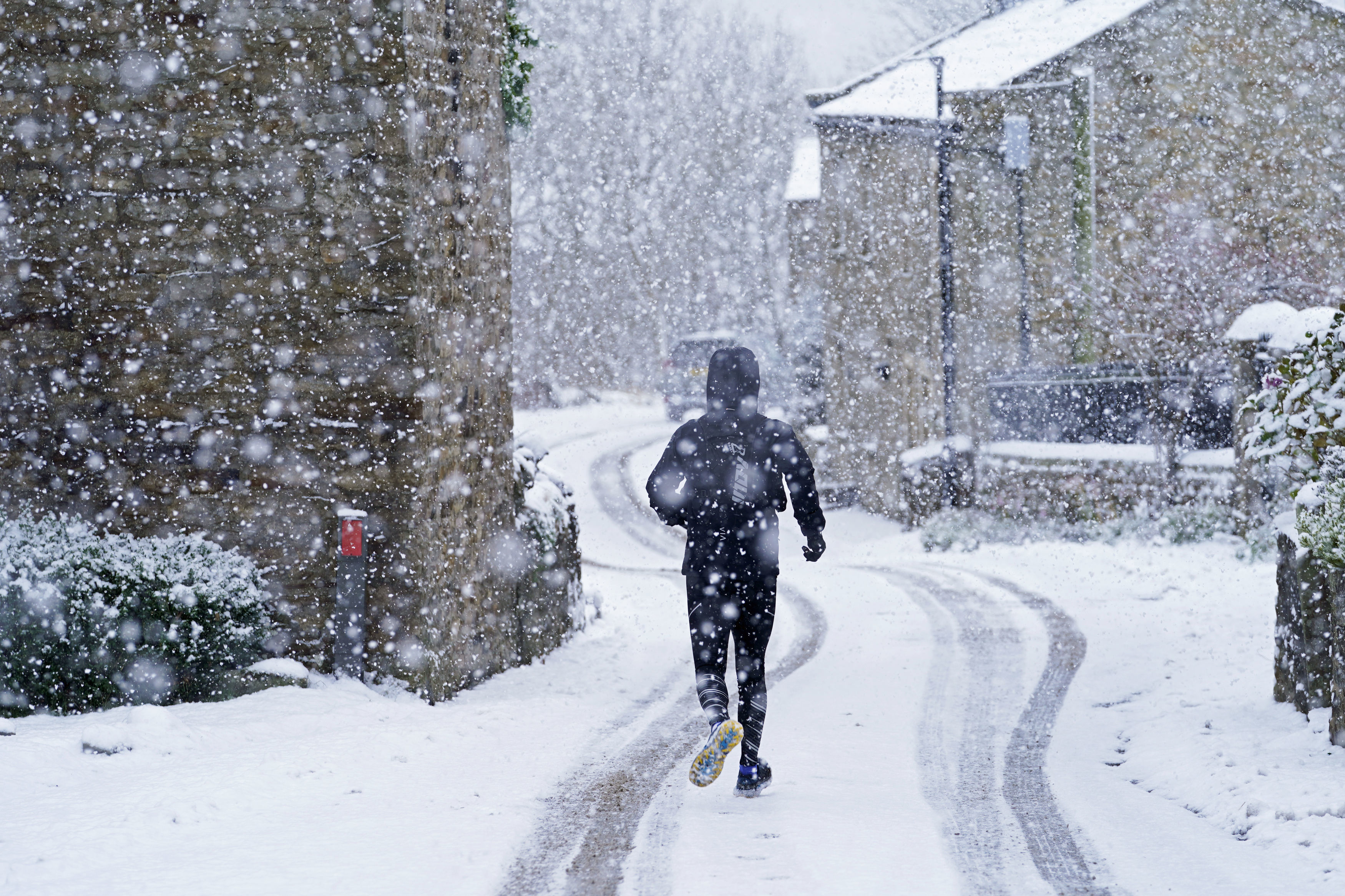 A man runs through the snow in Gunnerside, North Yorkshire